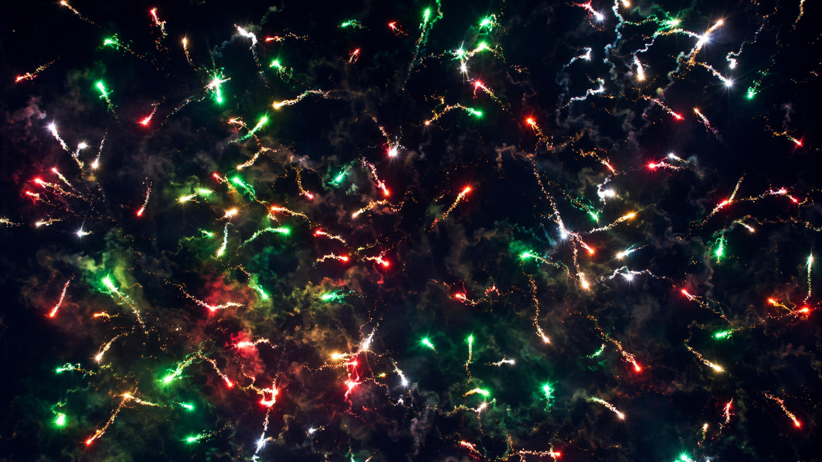 Bright red, green, and silver flying fish specialty fuse burning with fast, erratic squiggly light trails across a dark night sky.