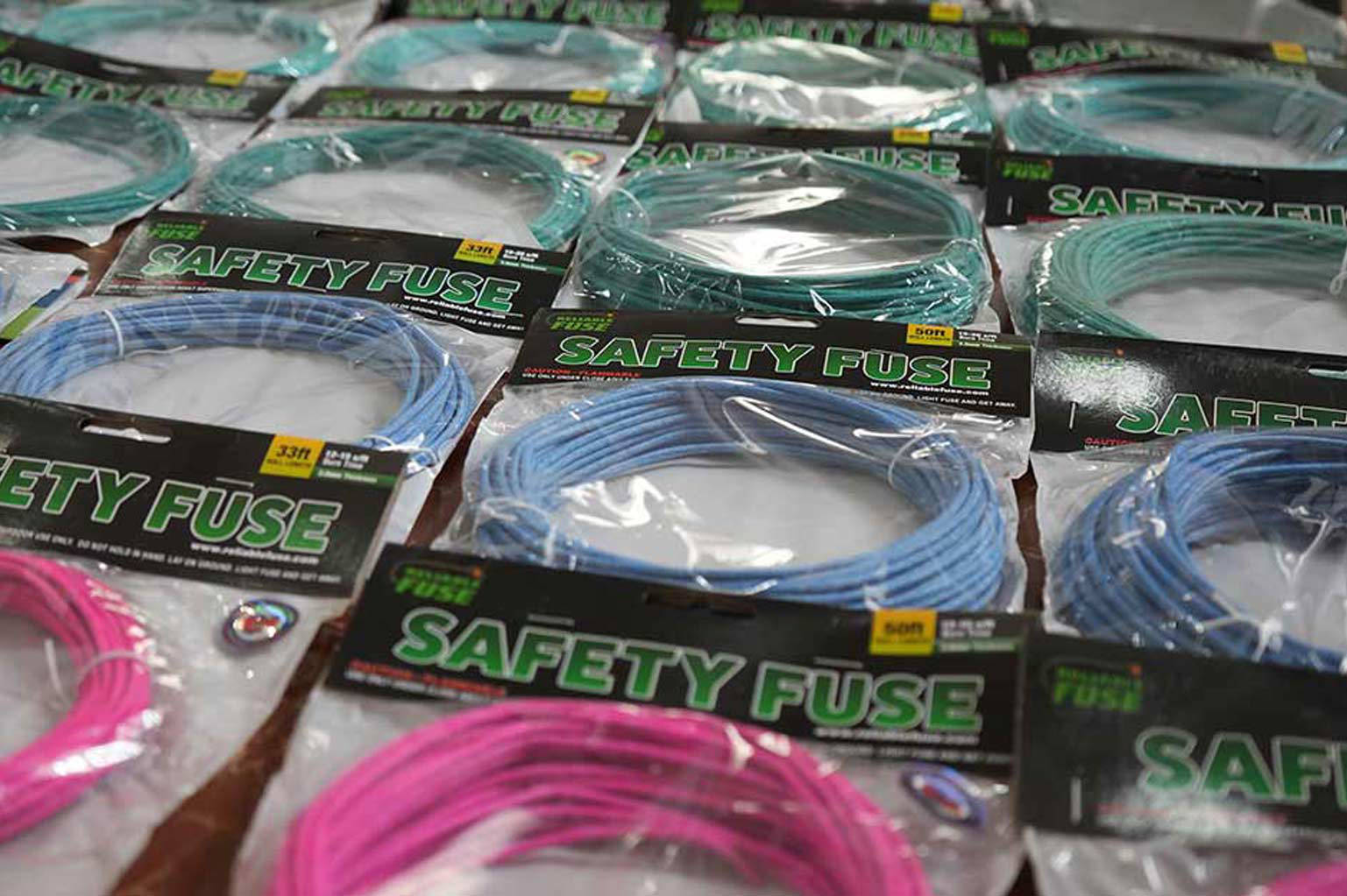 Multiple packaged rolls of Visco safety fuse in green, blue, and pink displaying burn rates and diameter specifications.